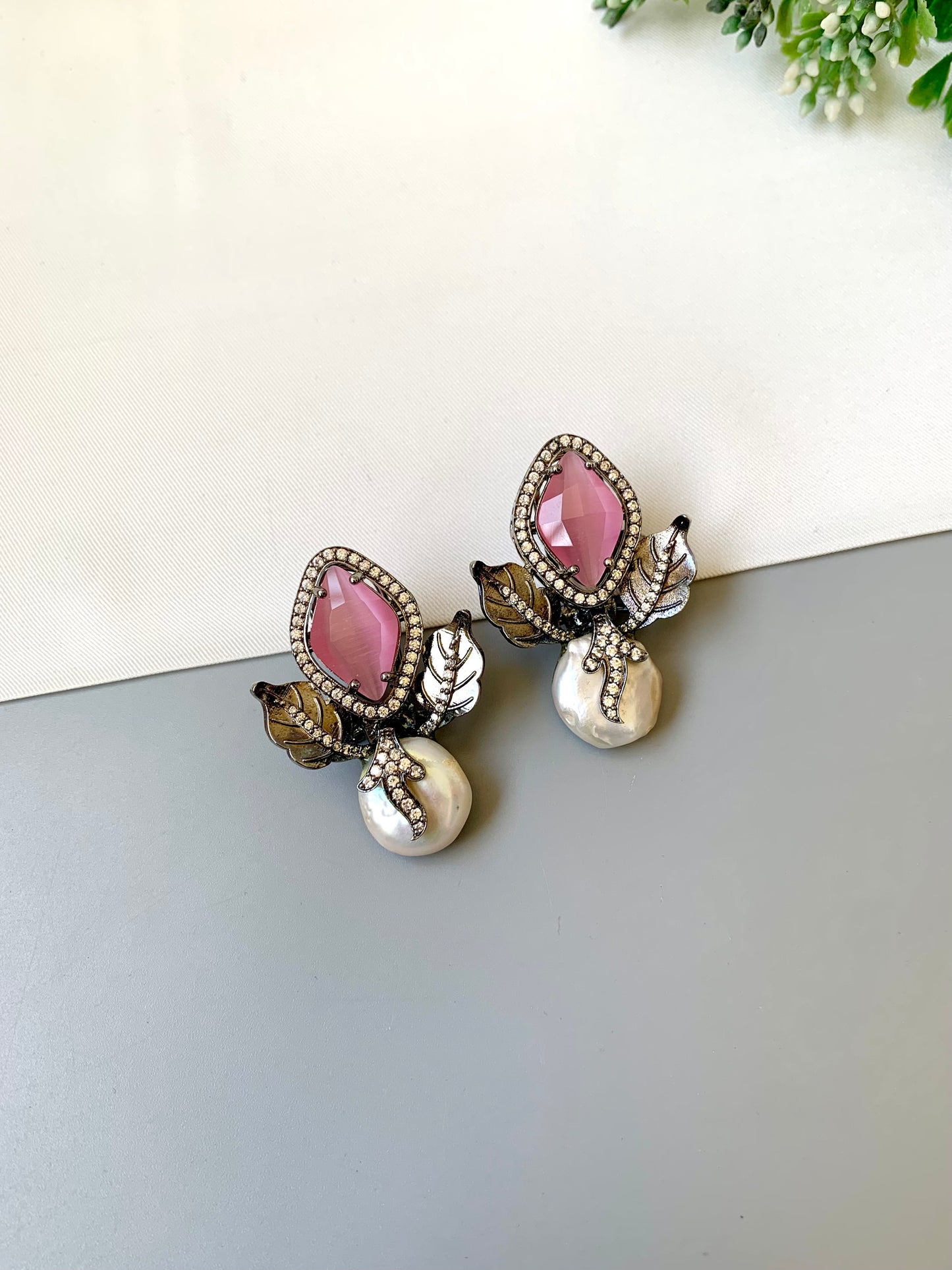 Pair of earrings with pink gemstones and pearl-like elements on a white surface.