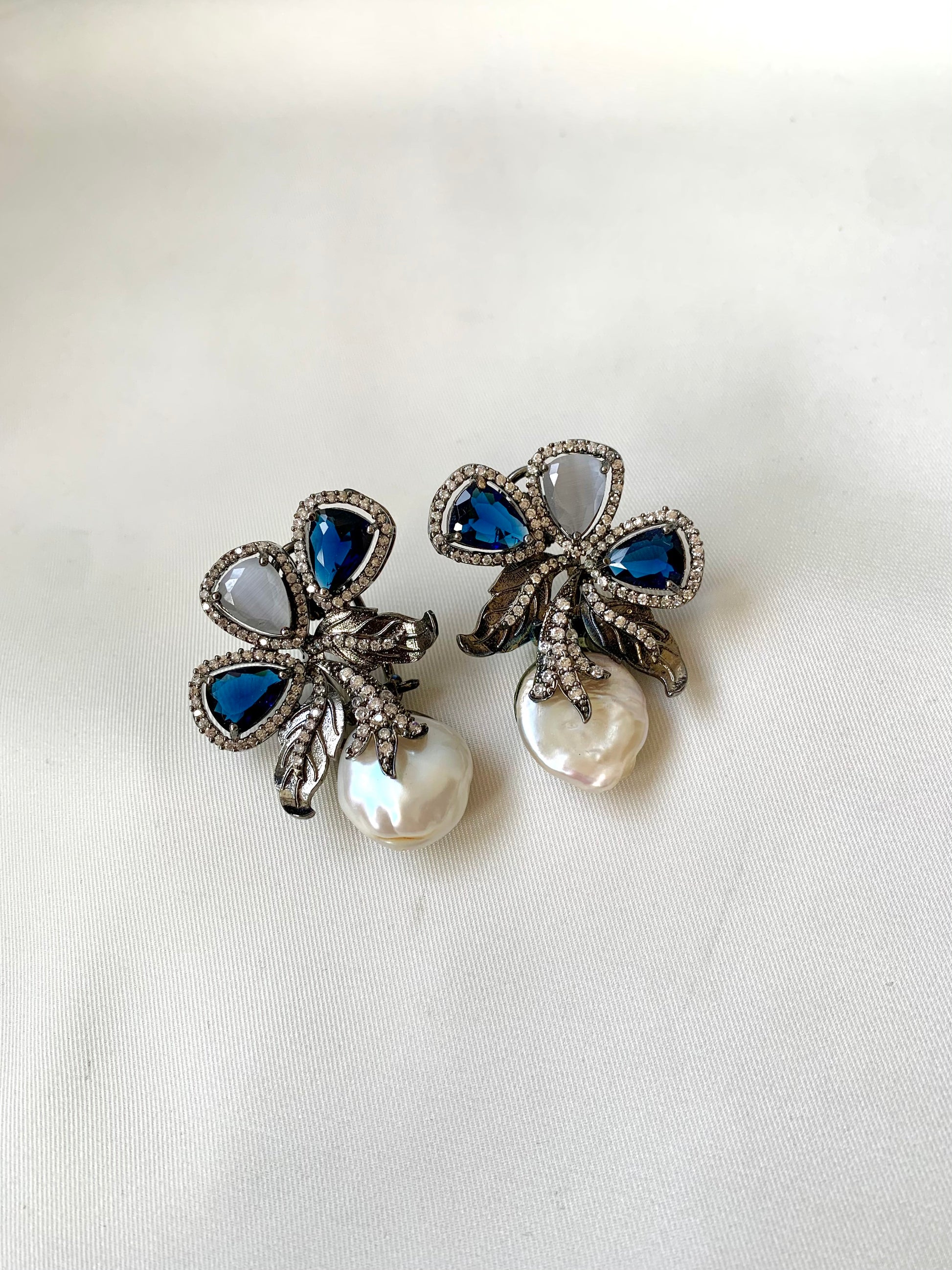 Pair of decorative earrings with blue and pearl elements on a white background