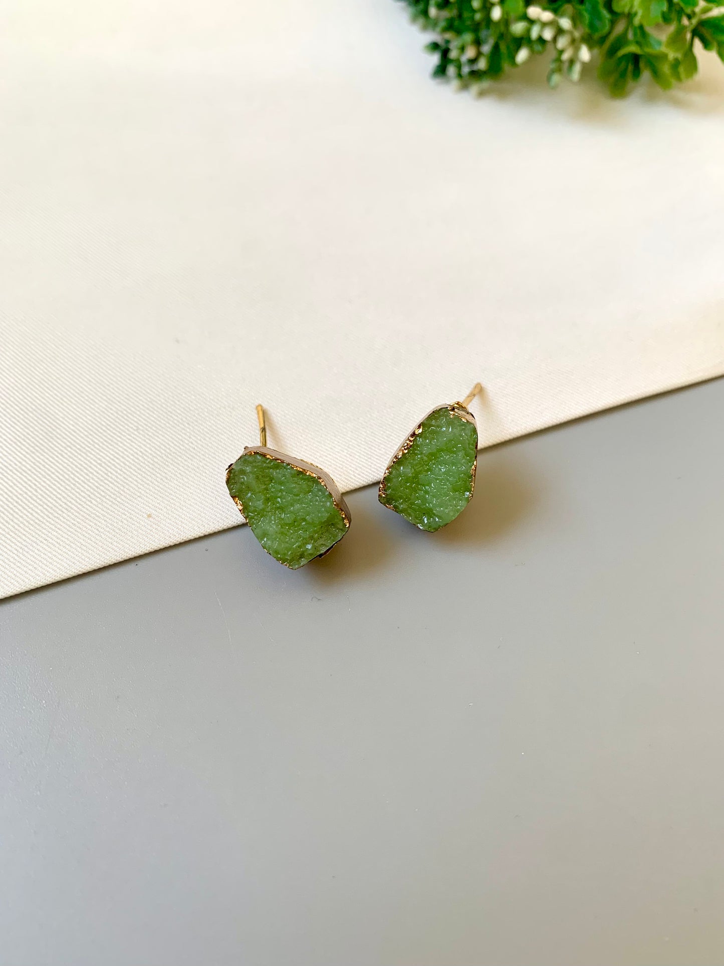 Green leaf-shaped earrings on a light background