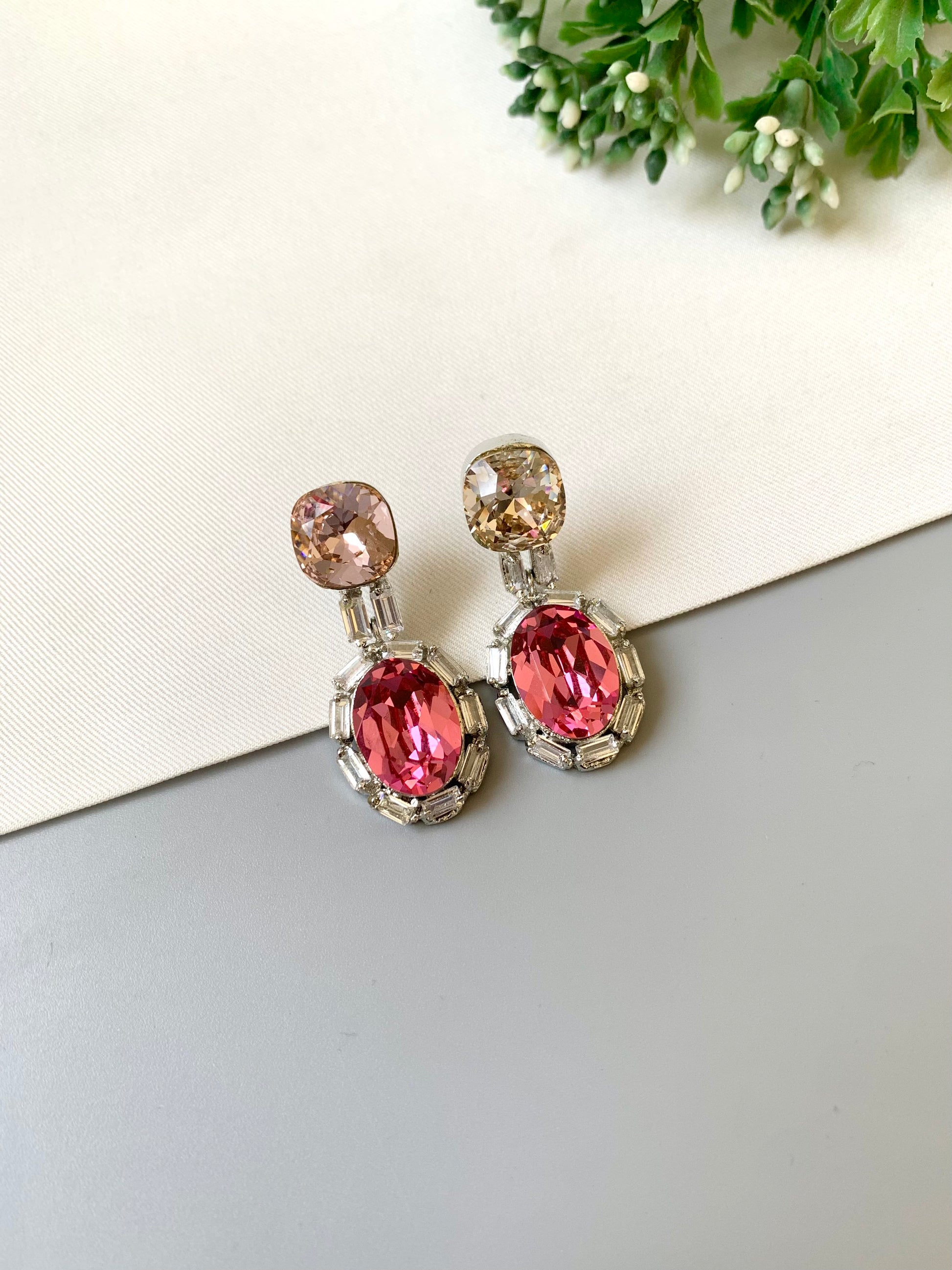 Pair of earrings with pink gemstones on a light background