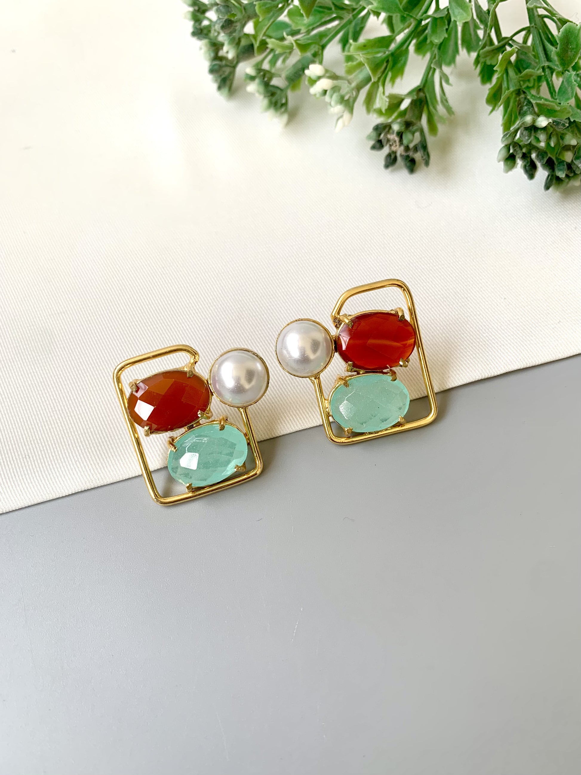 Pair of earrings with colorful gemstones on a neutral background