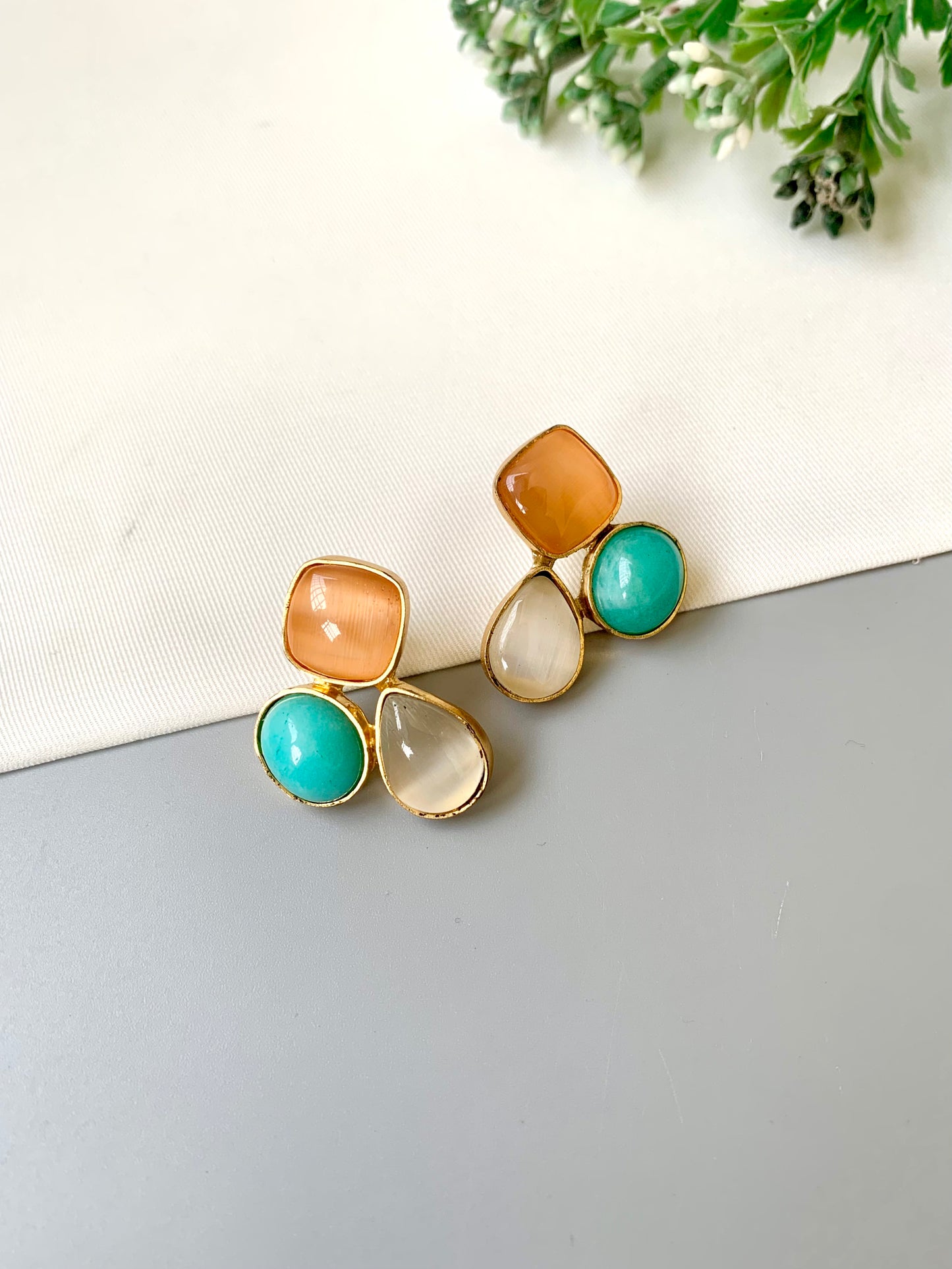 Pair of earrings with multicolored stones on a neutral background