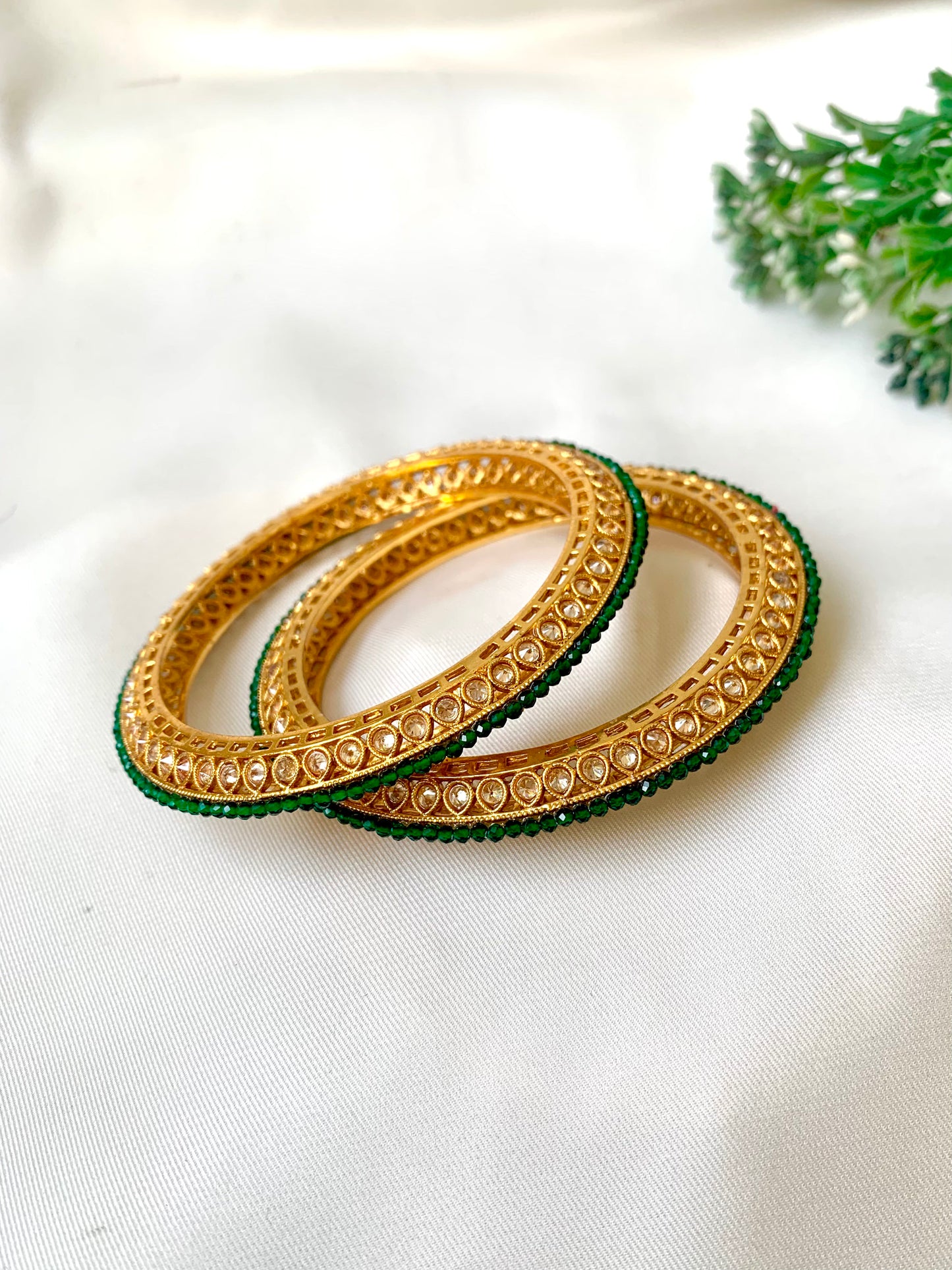 Handcrafted Ravira Bangles in 22kt gold plating with reverse American Diamonds and Semi-Precious Emeralds — by Zamal Jewels.