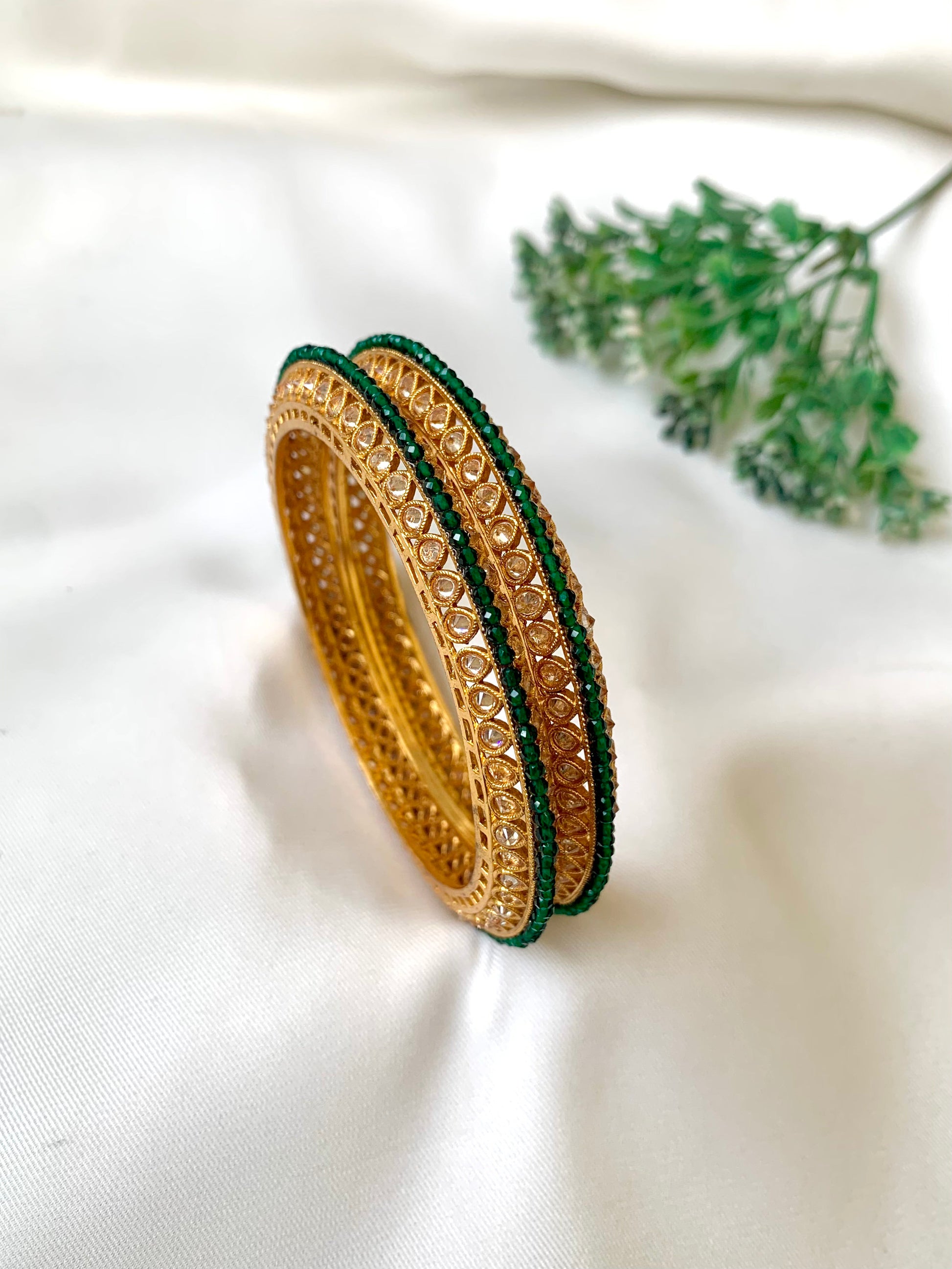 Handcrafted Ravira Bangles in 22kt gold plating with reverse American Diamonds and Semi-Precious Emeralds — by Zamal Jewels.