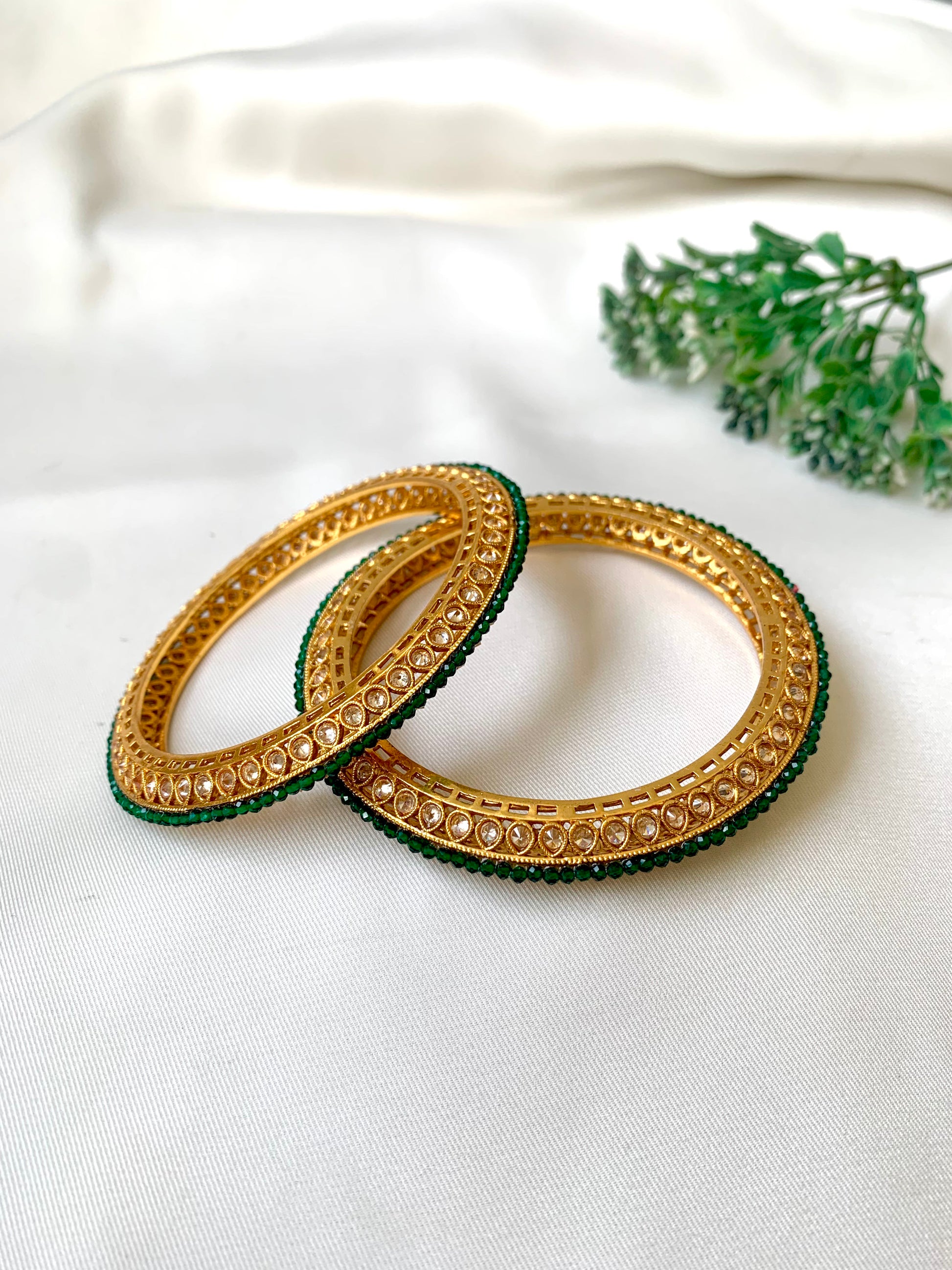 Handcrafted Ravira Bangles in 22kt gold plating with reverse American Diamonds and Semi-Precious Emeralds — by Zamal Jewels.