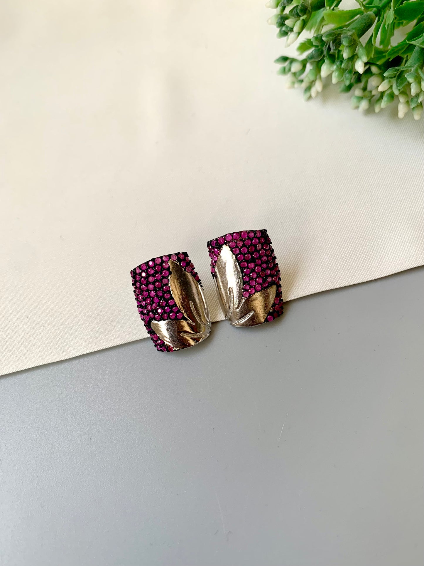 Pair of earrings with purple gemstones on a light gray surface.