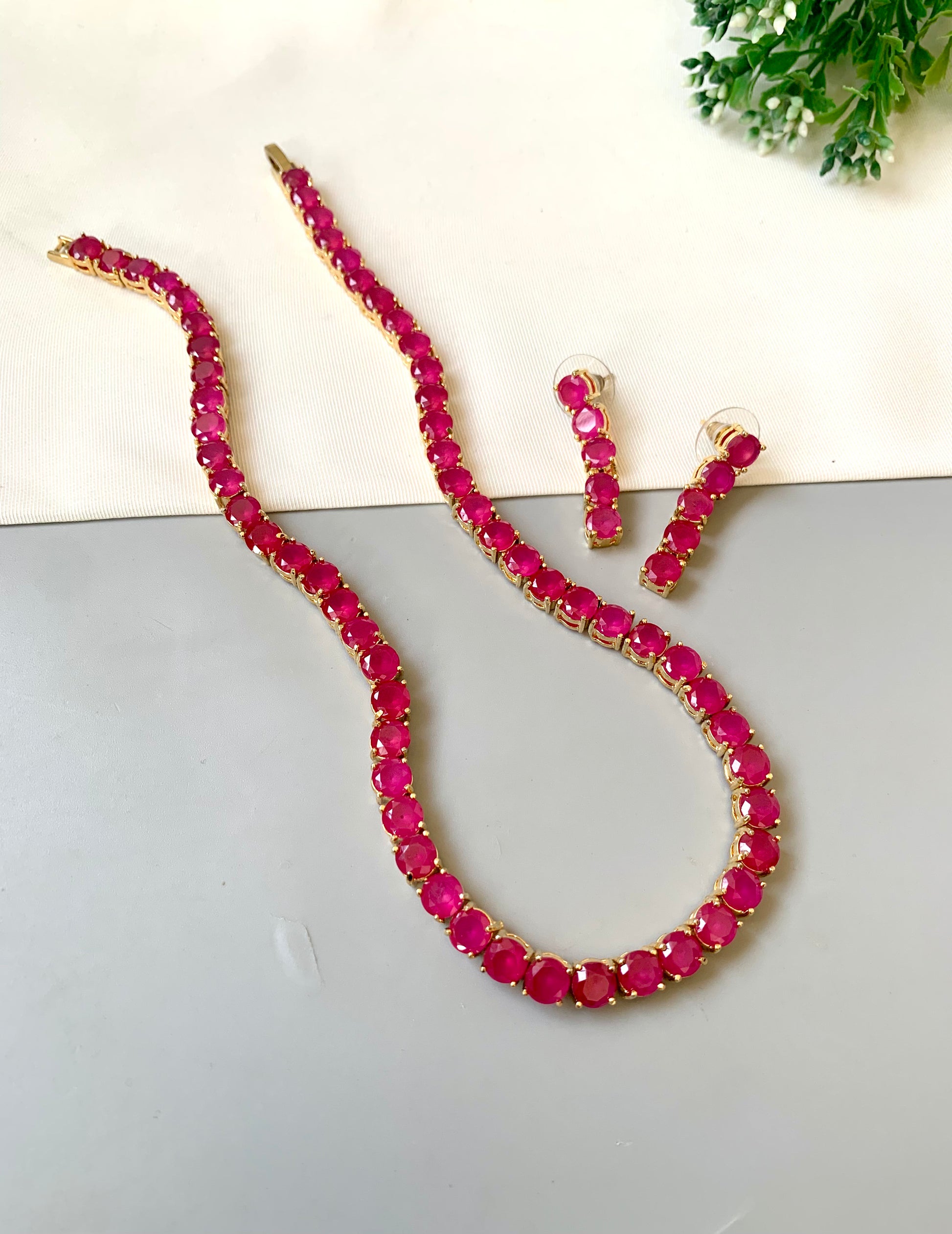 Necklace and earrings with red gemstones on a light background