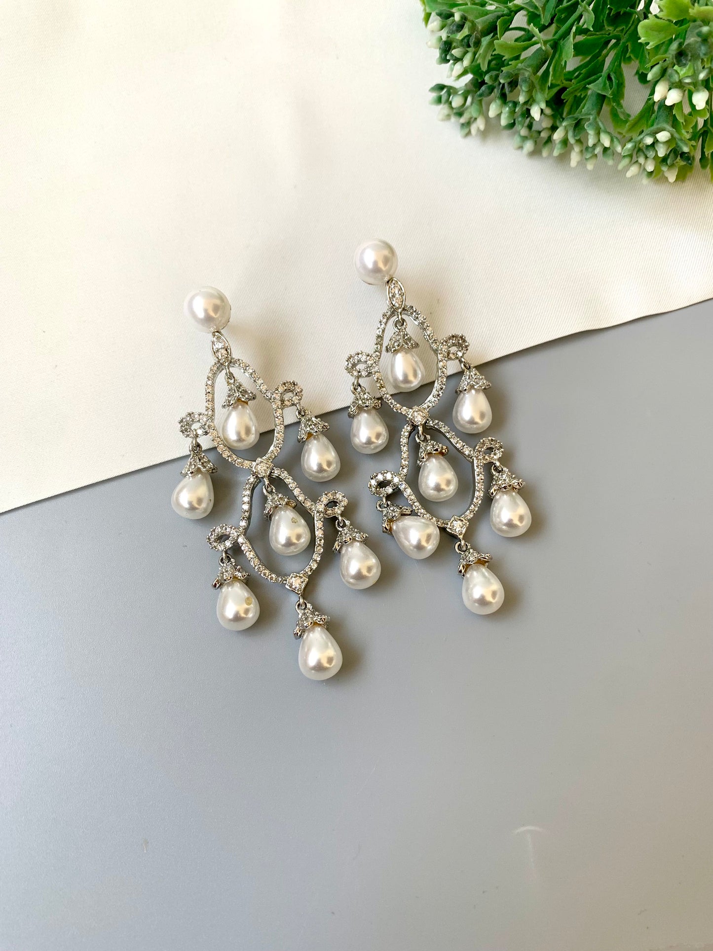Hand crafted rhodium plated earrings with diamond finish, American diamonds and semi-precious pearl detailing by Zamal