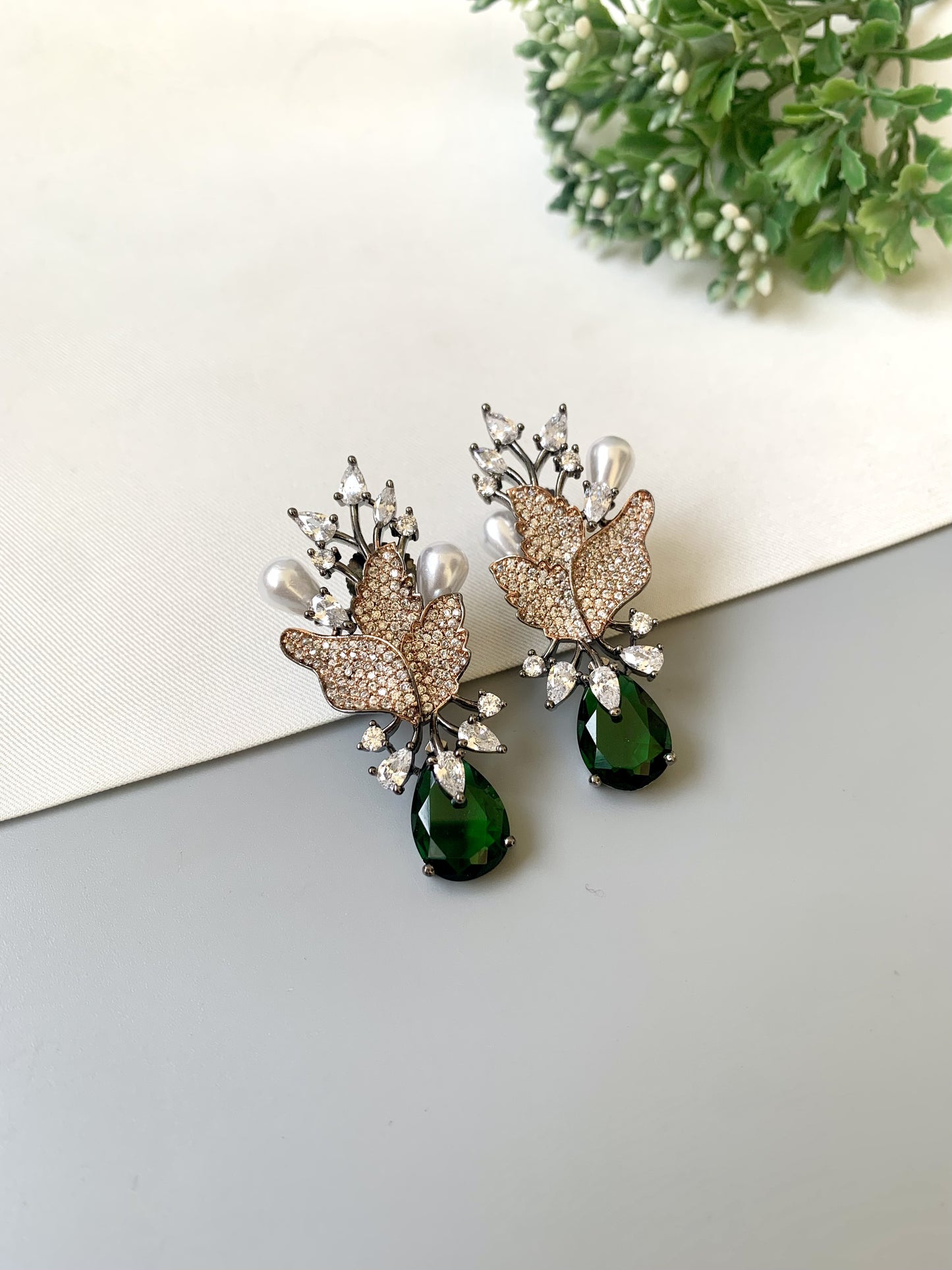Elegant earrings with green gemstones on a light surface