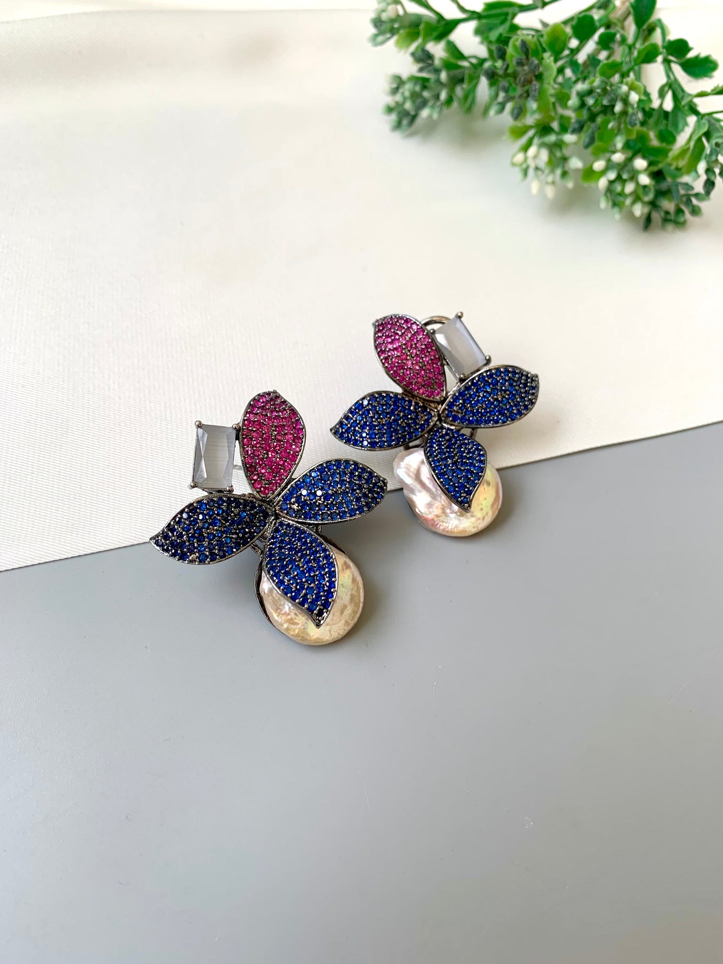 Butterfly-shaped earrings with colorful gemstones on a light surface.
