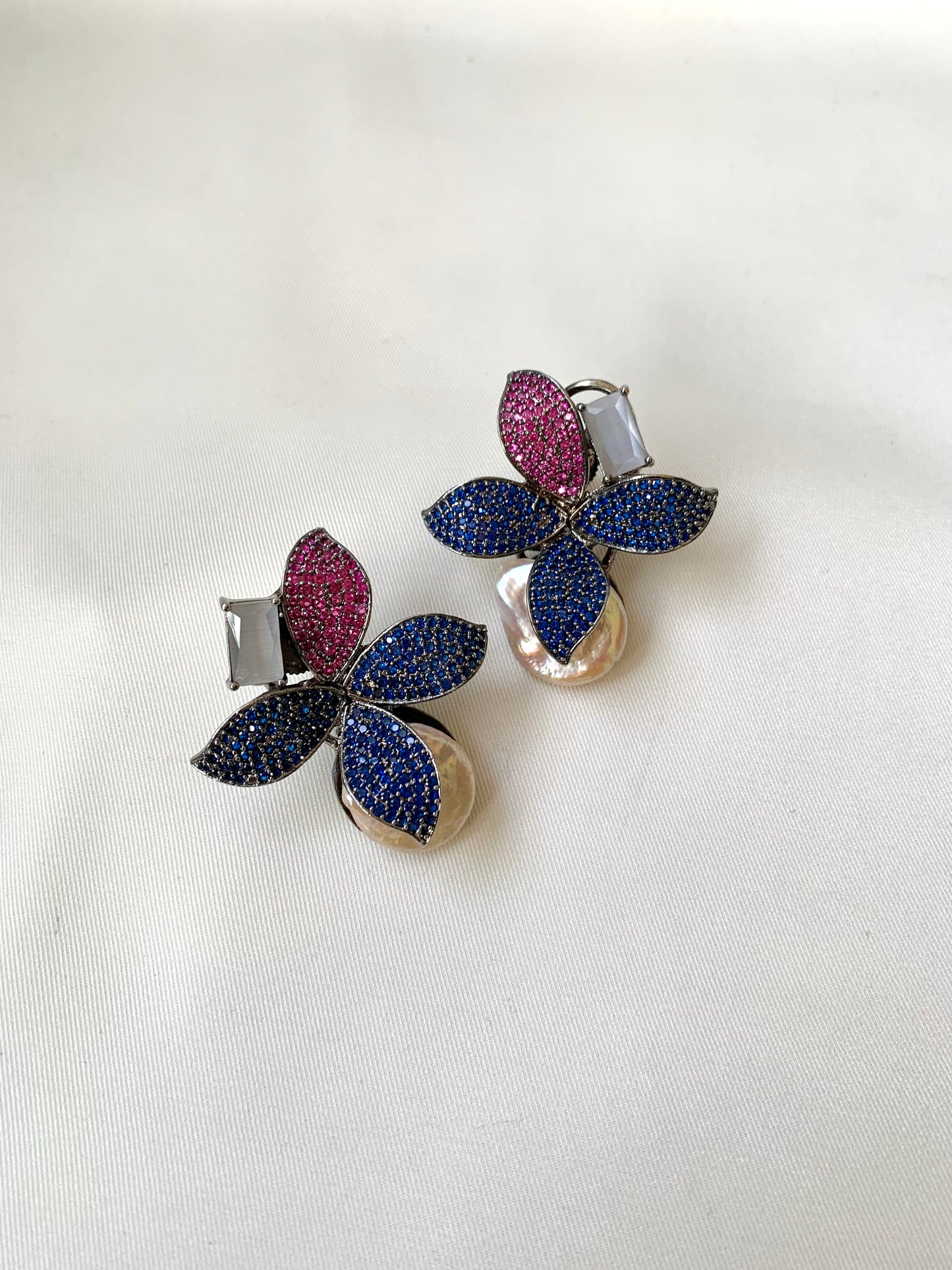 Pair of floral earrings with multicolored gemstones on a white background