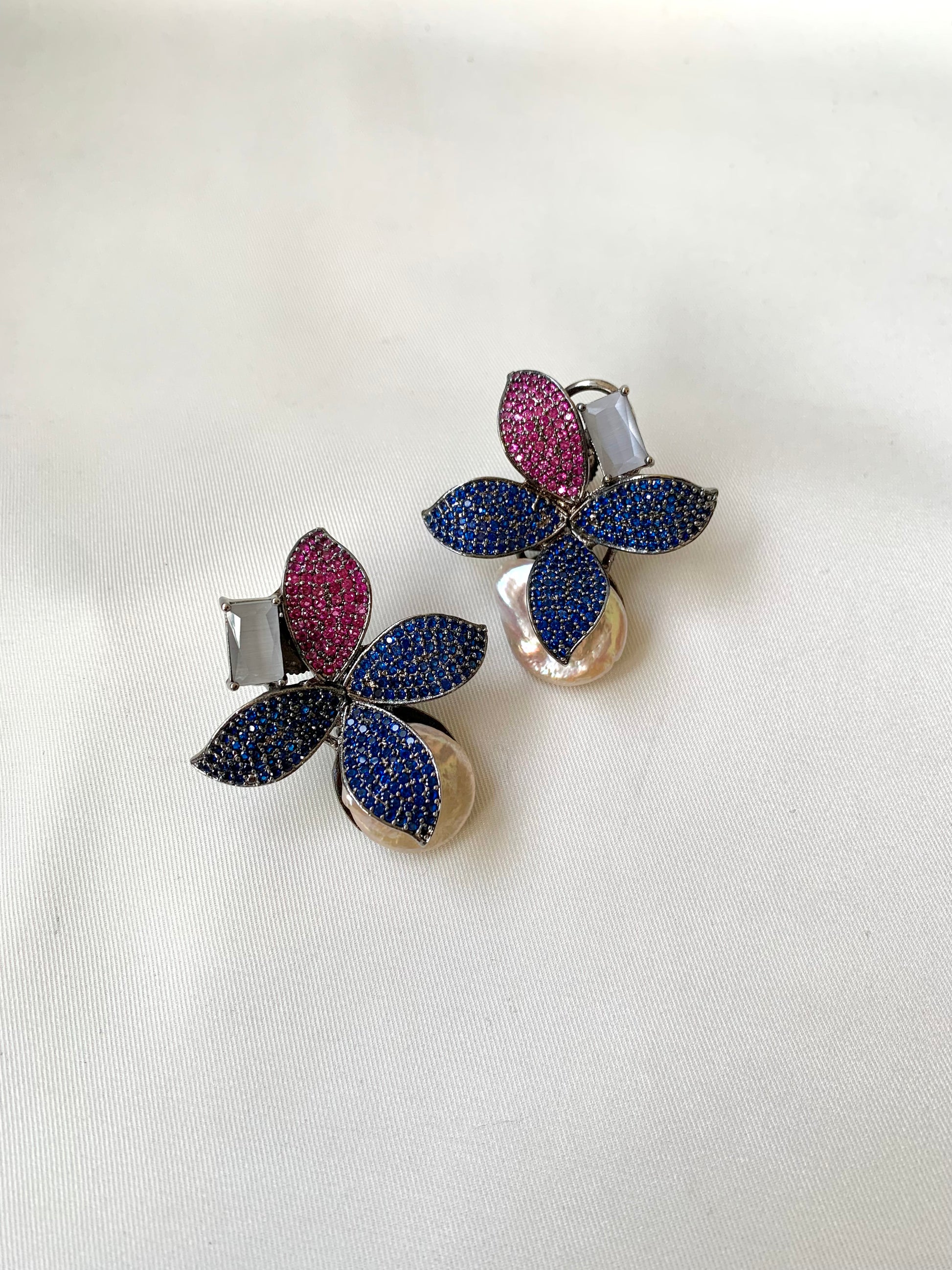 Pair of floral earrings with multicolored gemstones on a white background