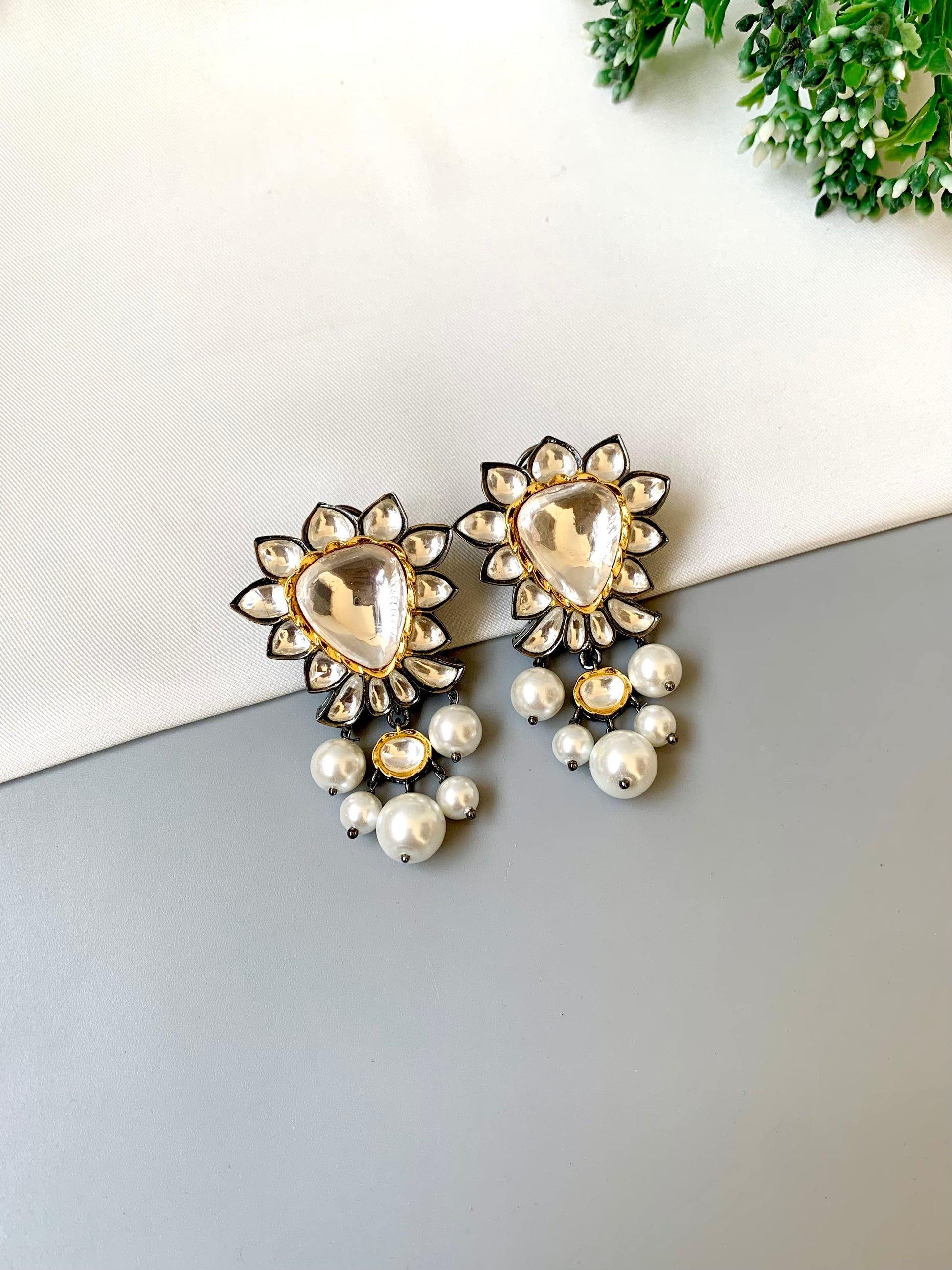 Pair of decorative earrings with pearl-like beads on a white and gray surface.